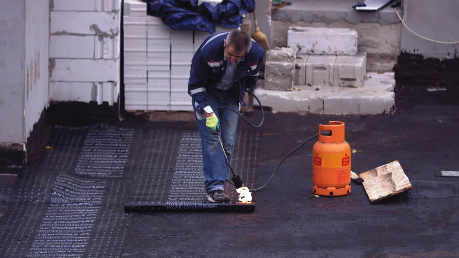 Abrams Renovation worker applying torch-on waterproofing on an East London roof